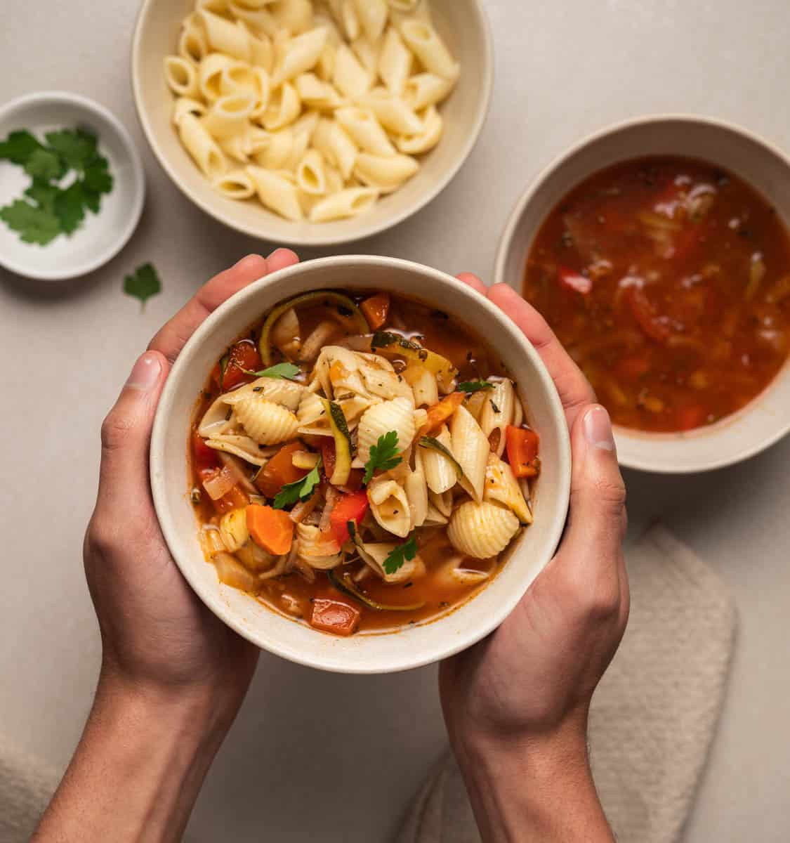 hands holding a bowl of pasta soup